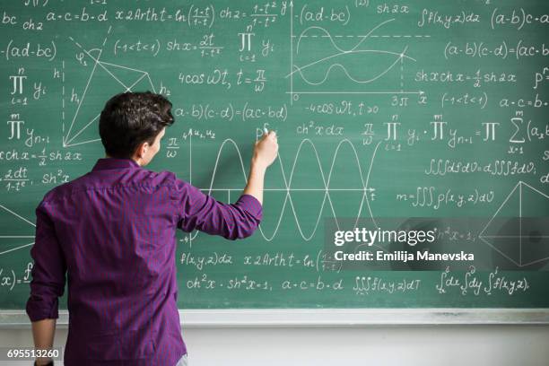 male student writing on blackboard - mathematik stock-fotos und bilder