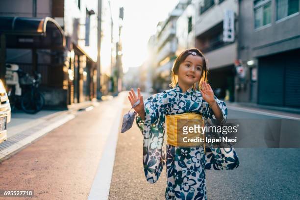adorable mixed race little girl in yukata dancing in the street, tokyo - yukata kimono stock-fotos und bilder