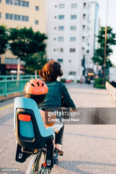 Mother cycling home with her child in city, Tokyo