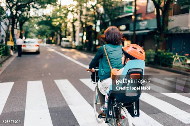 mother cycling home with her child in urban city, tokyo - candid city stock-fotos und bilder