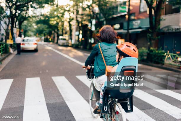 mother cycling home with her child in urban city, tokyo - famille a velo photos et images de collection