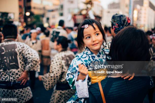 Cute mixed race little girl in yukata with her mother at traditional festival in Tokyo
