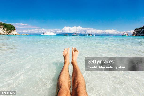 personal perspective of man's feet in clear turquoise water - legs stockfoto's en -beelden