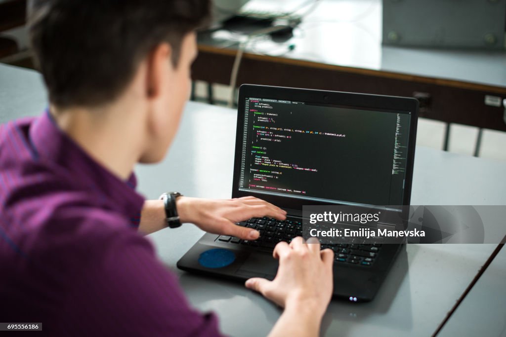 Young man using his laptop to try to solve problem with code