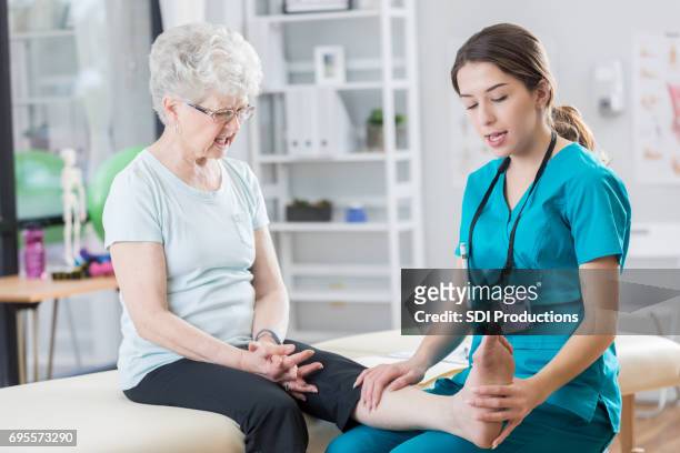 vertrouwen vrouwelijke fysiotherapeut helpt vrouw haar been rekken - old lady feet stockfoto's en -beelden