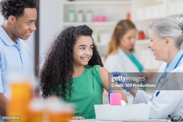 cheerful girl prepares to receive back to school vaccines - flu vaccine stock pictures, royalty-free photos & images