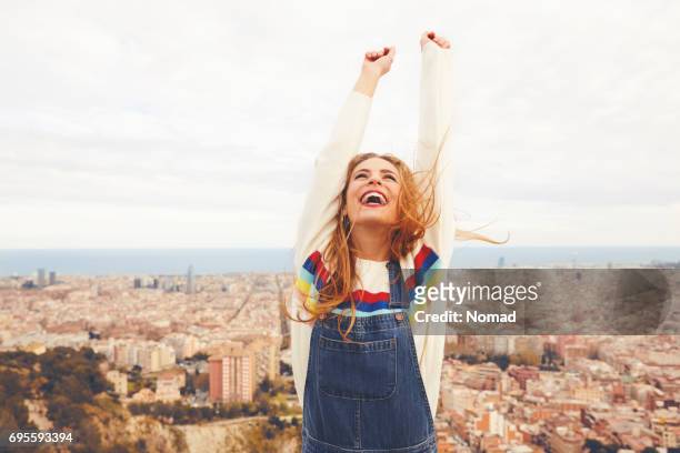 mujer feliz con los brazos alzados contra el paisaje urbano - leisure activity fotografías e imágenes de stock