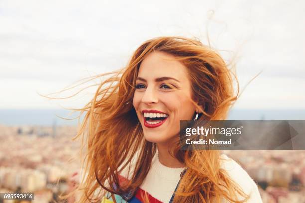 cheerful woman with tousled hair against cityscape - toothy smile stock pictures, royalty-free photos & images