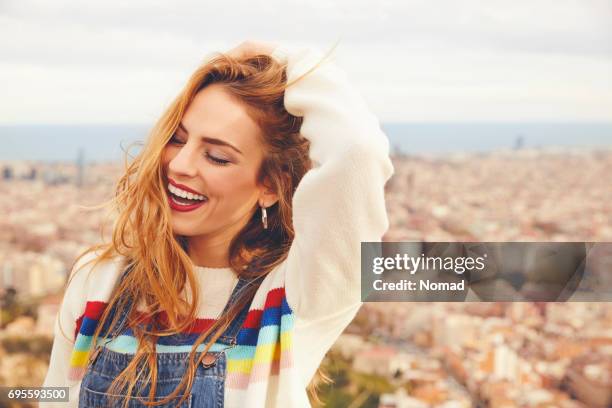 lächelnde frau mit hand im haar gegen stadtbild - hand in den haaren stock-fotos und bilder