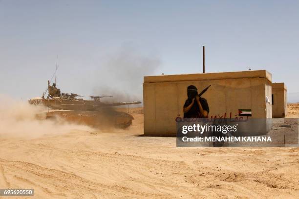 Israeli soldiers manoeuver a tank next to a building simulating an enemy village during a military training near Shizafon army camp in the southern...