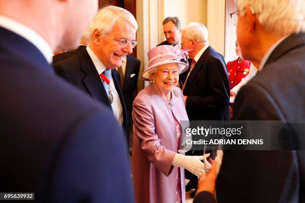 Britain's Queen Elizabeth II greets guests including former prime minister John Major at a reception after an Evensong service in celebration of the...