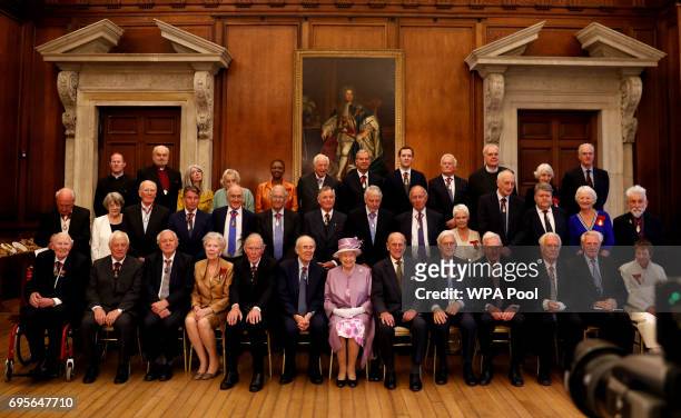 Queen Elizabeth II sits next to Prince Philip, Duke of Edinburgh during an official photograph with Companions of Honour after a reception in...