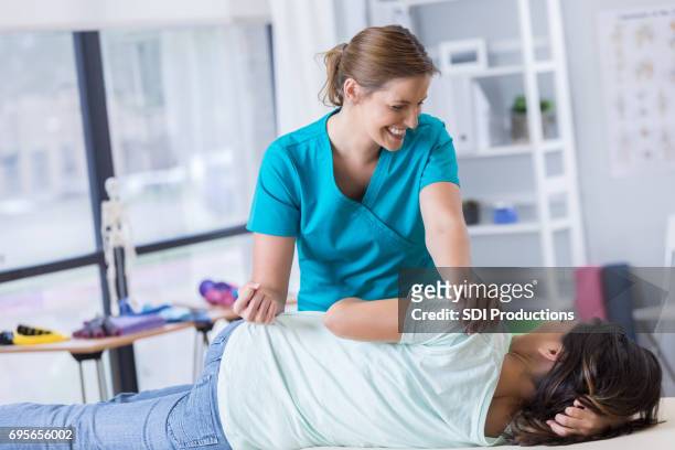 chiropractor or physical therapist works with female patient - hip stock pictures, royalty-free photos & images