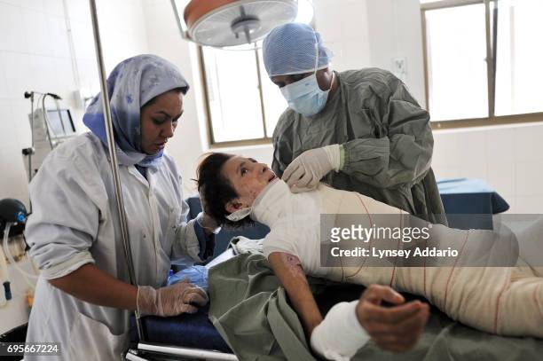 Hanife is comforted by nurse Fatima Mohammadi as she has her bandages changed by nurse Zalmai Hashimi for the first time since undergoing skin graft...
