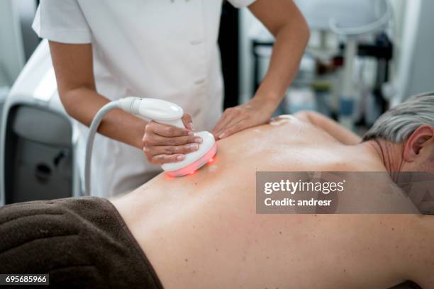 man laserbehandeling krijgt op zijn rug in de spa - medical laser stockfoto's en -beelden