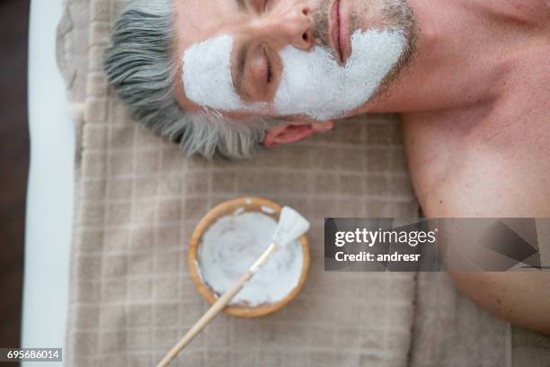 hombre conseguir una máscara facial en el spa - spa treatment fotografías e imágenes de stock