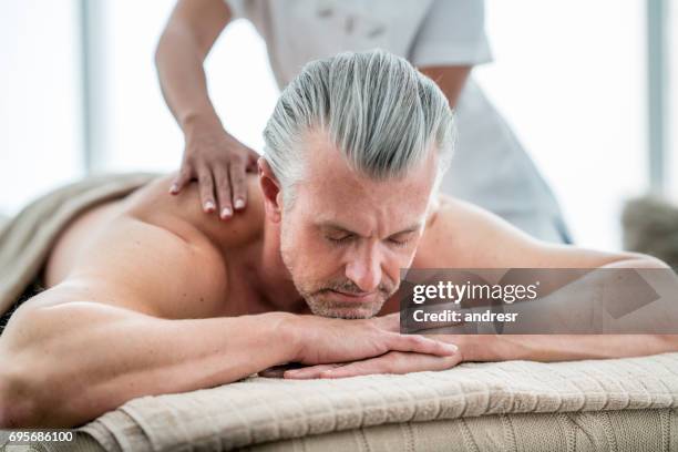 homem relaxante no spa recebendo uma massagem - massagista - fotografias e filmes do acervo