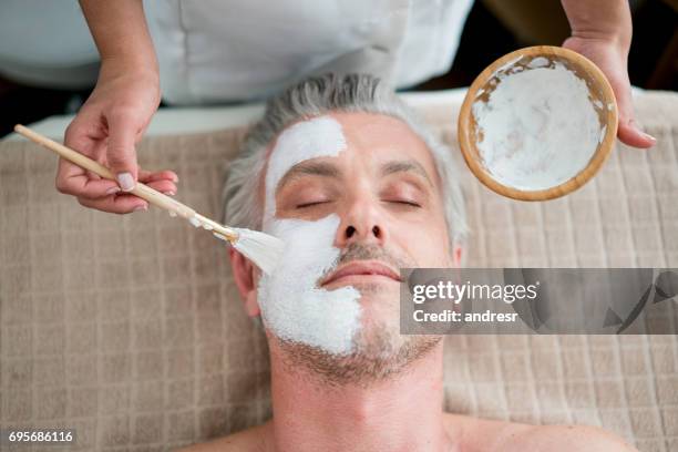 man getting a facemask at the spa - mask man stock pictures, royalty-free photos & images