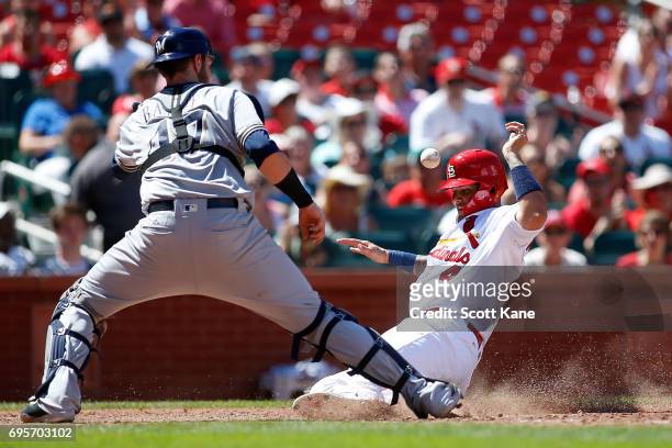 Catcher Jett Bandy of the Milwaukee Brewers waits for the ball as Yadier Molina of the St. Louis Cardinals scores a run during the sixth inning at...
