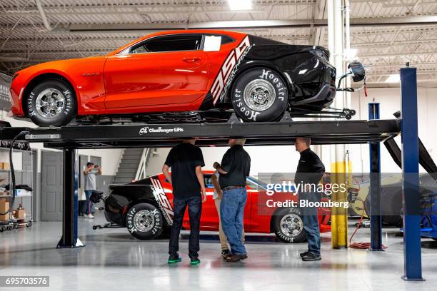 Lottery winner Kevin Mitchell, center, views the undercarriage of his new General Motors Co. Chevrolet COPO Camaro inside the company's build center...