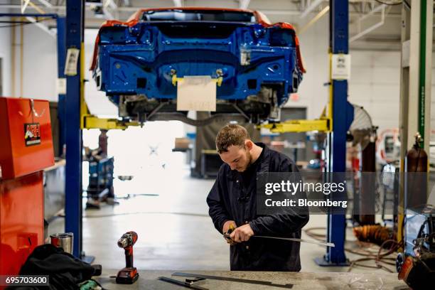 An employee cuts metal while working on a the chassis of a General Motors Co. Chevrolet COPO Camaro performance vehicle at the company's build center...