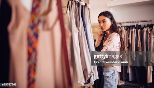 asiatische hipster frau shopping für kleidung in einem bekleidungsgeschäft - buying clothes stock-fotos und bilder