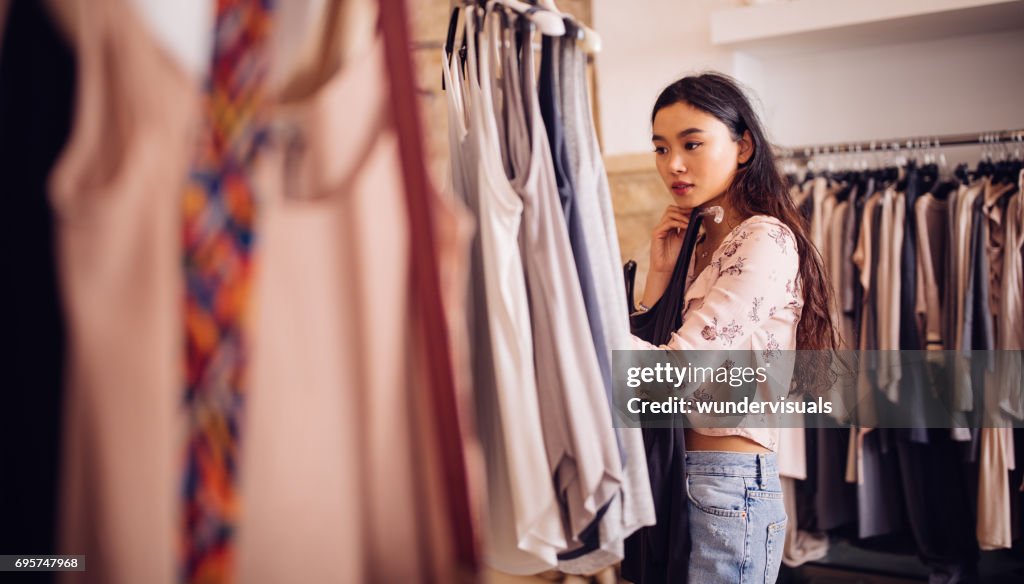 Asian hipster woman shopping for clothes inside a clothing store