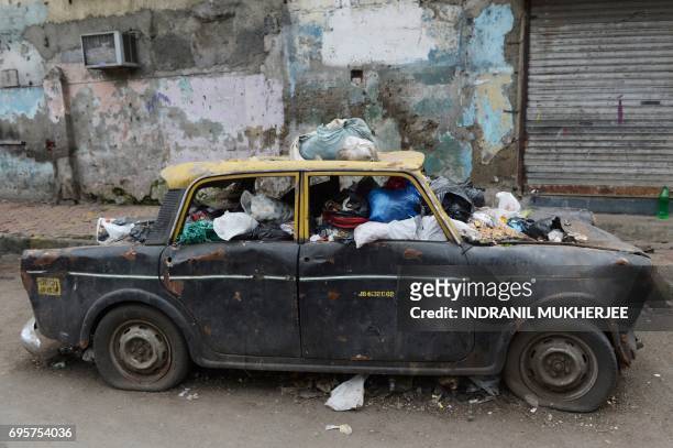 In this photograph taken on August 19 a Premiere Padmini taxi used as a garbage vat is seen along a street in the Indian city of Mumbai. They were...
