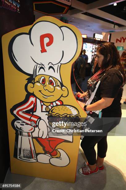 Attendee Mary Esslinger plays a classic stand up arcade game during the Electronic Entertainment Expo E3 at the Los Angeles Convention Center on June...