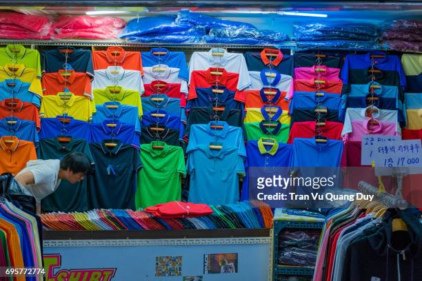the man is selling colorful t-shirts. - dried herring stock pictures, royalty-free photos & images