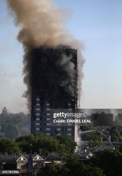 Smoke billows from Grenfell Tower as firefighters attempt to control a huge blaze on June 14, 2017 in west London. - The massive fire ripped through...