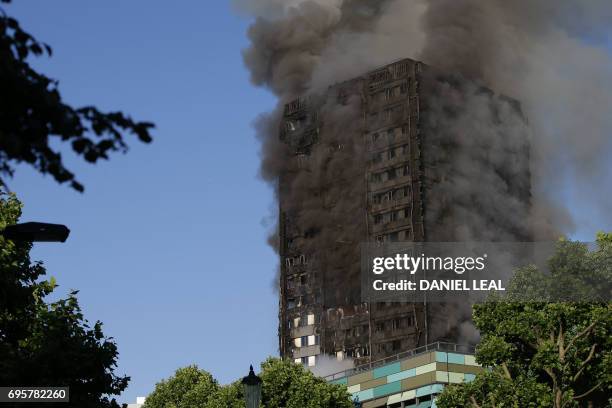 Smoke billows from Grenfell Tower as firefighters attempt to control a huge blaze on June 14, 2017 in west London. - The massive fire ripped through...