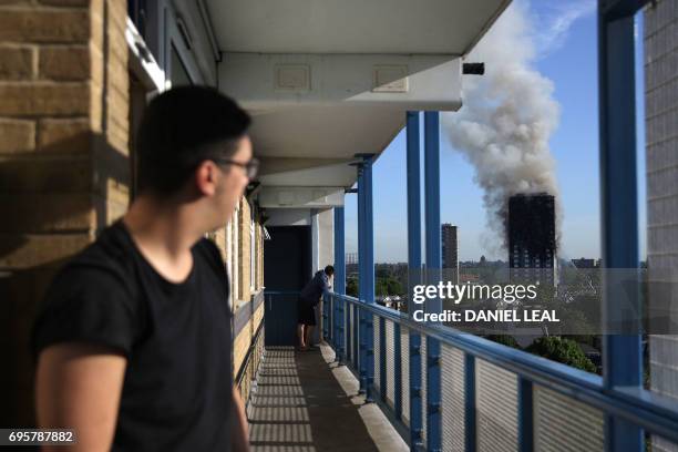 Resident of a nearby council estate watches smoke billowing from Grenfell Tower on June 14, 2017 in west London. The massive fire ripped through the...