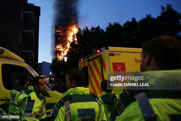 Members of the emergency services watch as Grenfell Tower is engulfed by fire on June 14, 2017 in west London. The massive fire ripped through the...