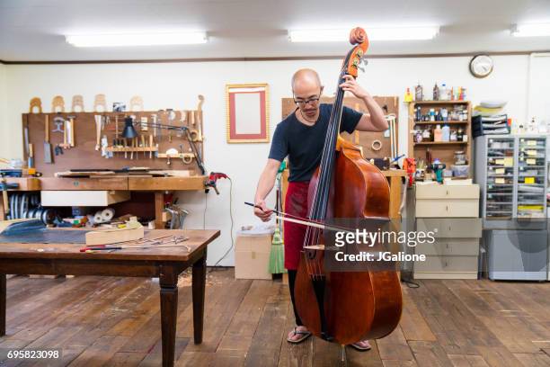 ambachtsman testen een contrabas in zijn atelier - bassoon stockfoto's en -beelden