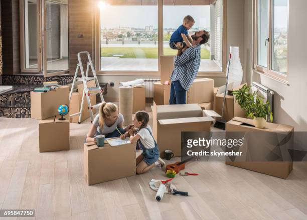 happy parents having fun with their small kids in their new apartment. - penthouse girl stock pictures, royalty-free photos & images