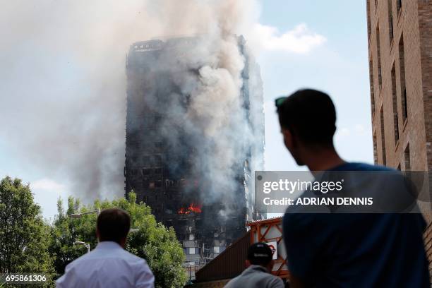 Pedestrians look up towards Grenfell Tower, a residential block of flats in west London on June 14 as firefighters continue to control a fire that...