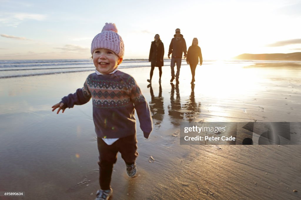 Family walking on beach at sunset