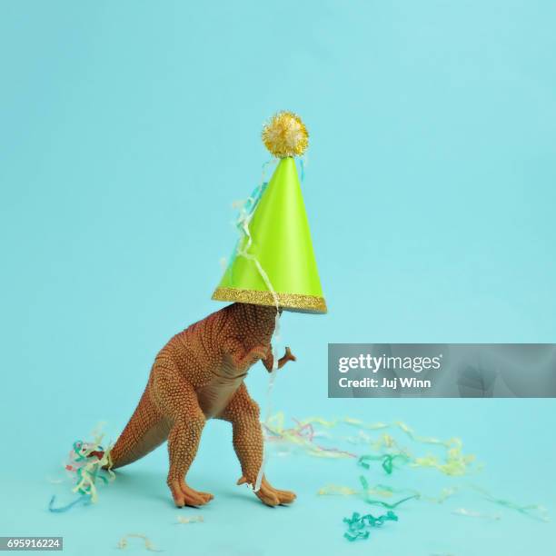 toy dinosaur wearing a party hat - party hat stock pictures, royalty-free photos & images