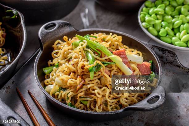 yakisoba, japanse pan gebakken noedels, met ham en lente-ui in gietijzer pot - rookkaas stockfoto's en -beelden