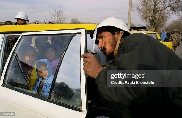 An Afghan policeman uses a knife to take off the tinted plastic on a car window January 30, 2002 in the center of Kabul, Afghanistan. The Afghan...