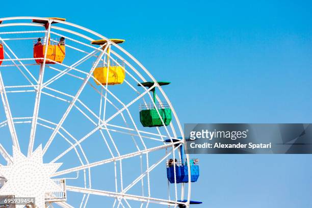 colorful ferris wheel against clear blue sky - noria fotografías e imágenes de stock