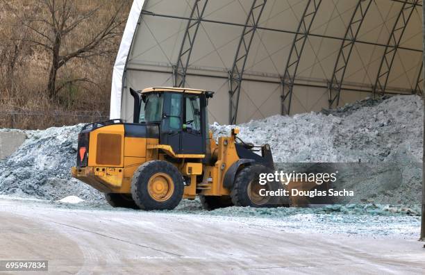 heavy duty wheeled excavator scoops rock salt from the storage dome - salz streuen stock-fotos und bilder