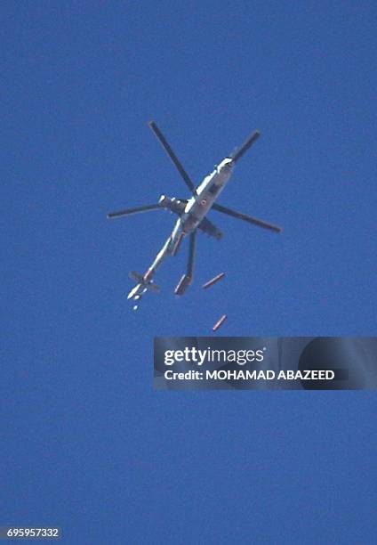 Syrian army helicopter drops barrel bombs on a rebel-held area in the southern city of Daraa, on June 14, 2017.