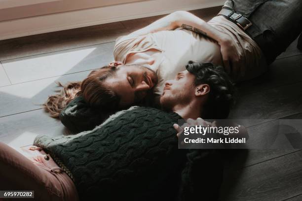 Gay couple lying on floor holding one another.
