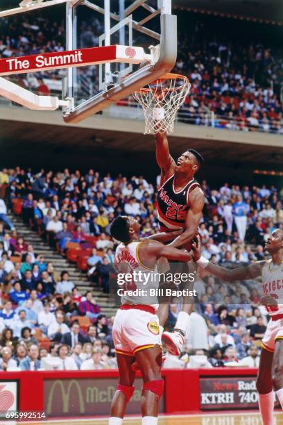Jerome Kersey of the Portland Trail Blazers dunks against Hakeem Olajuwon of the Houston Rockets during a game played circa 1990 at the Summit in...