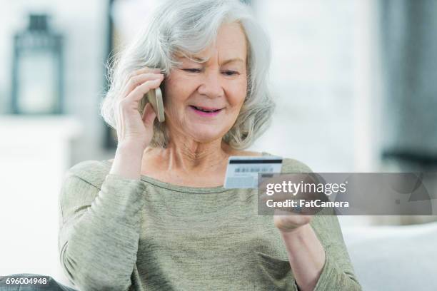 senior woman making a call with credit card - debit card fraud stock pictures, royalty-free photos & images