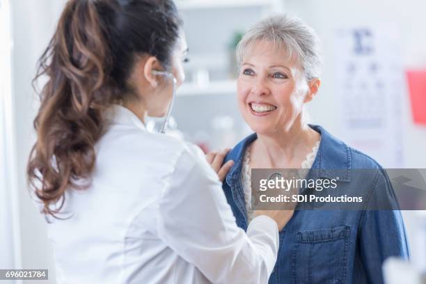 femme médecin écoute cardiaque du patient senior - adult patient with doctor and stethoscope photos et images de collection