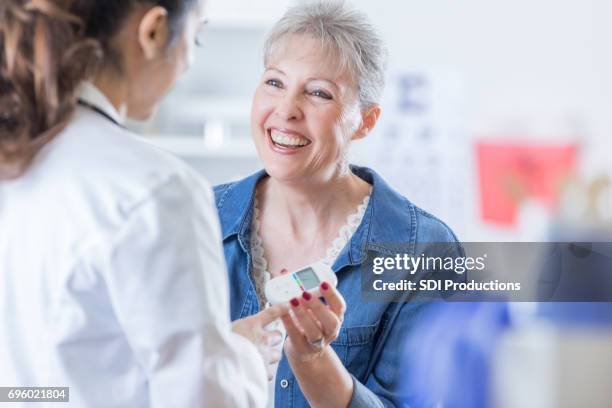 femme senior joyeuse discute quelque chose avec son médecin - système endocrinien photos et images de collection
