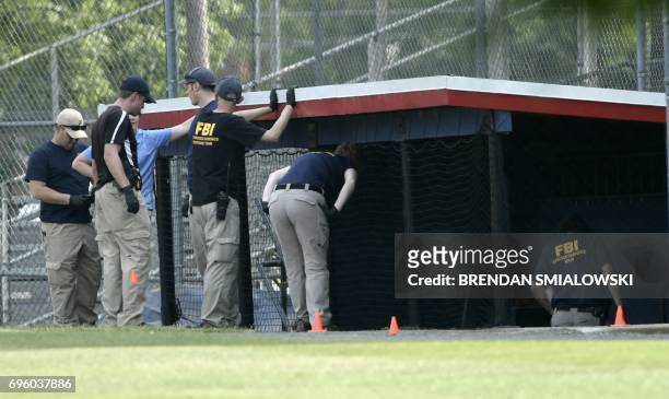 And other law enforcement officials inspect the crime scene after a shooting during a practice of the Republican congressional baseball game at...